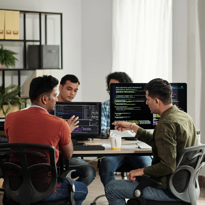 Un groupe de jeunes entrepreneurs assis autour d’une table d’ordinateurs en train de travailler.