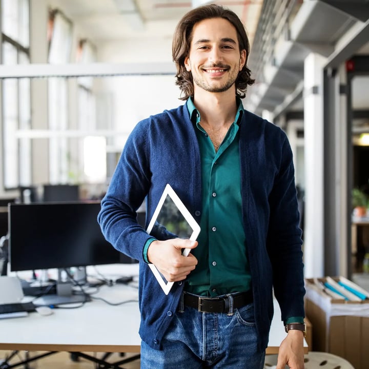 Une PME souriante se tient avec assurance à une table dans un bureau, face à la caméra.