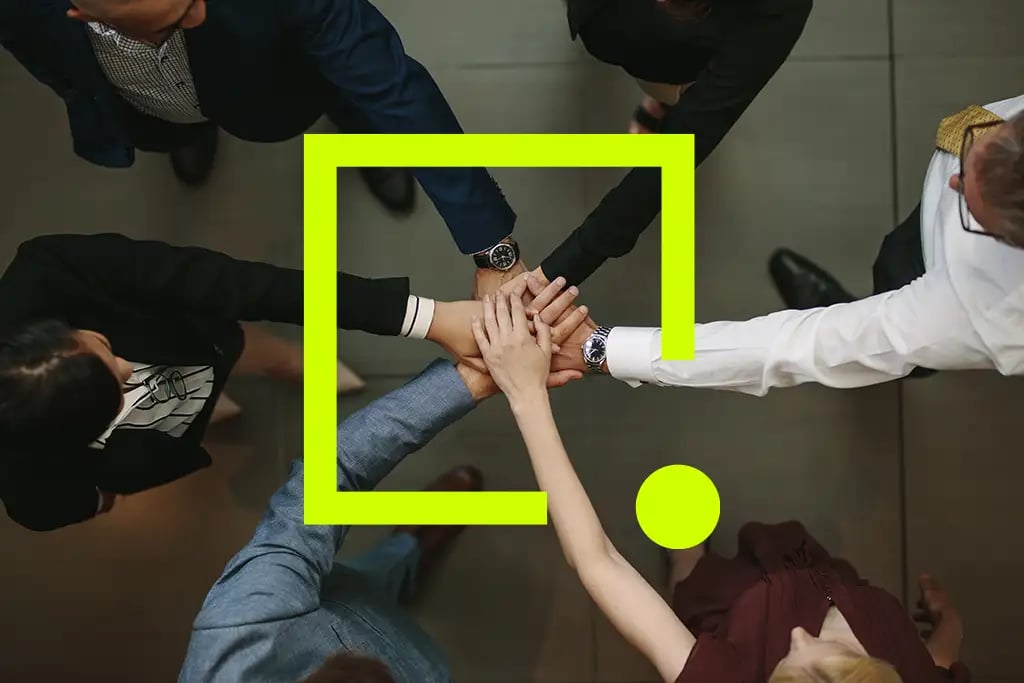 A group of business professionals standing in a circle, joining hands in a gesture of unity and collaboration.