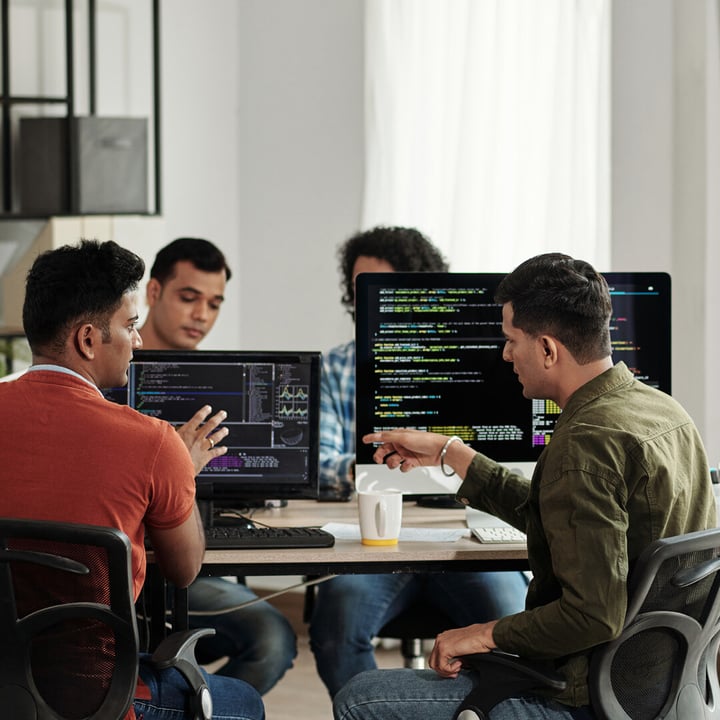 A group of young entrepreneurs sitting aroung table of computers working